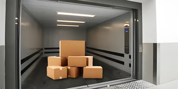 Freight elevator interior with cardboard boxes, ready for transport, serving as a banner image for goods lifting solutions.
